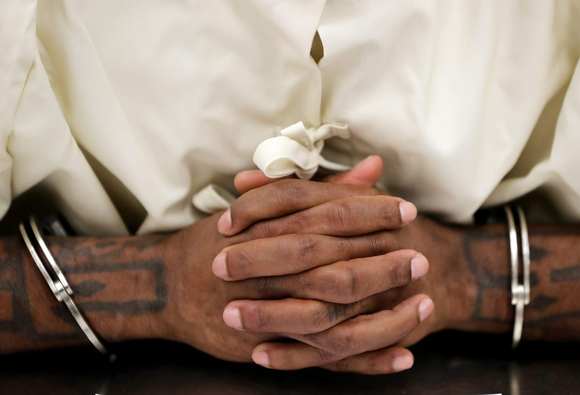 color photograph of a Black person's hands intertwined while wearing handcuffs