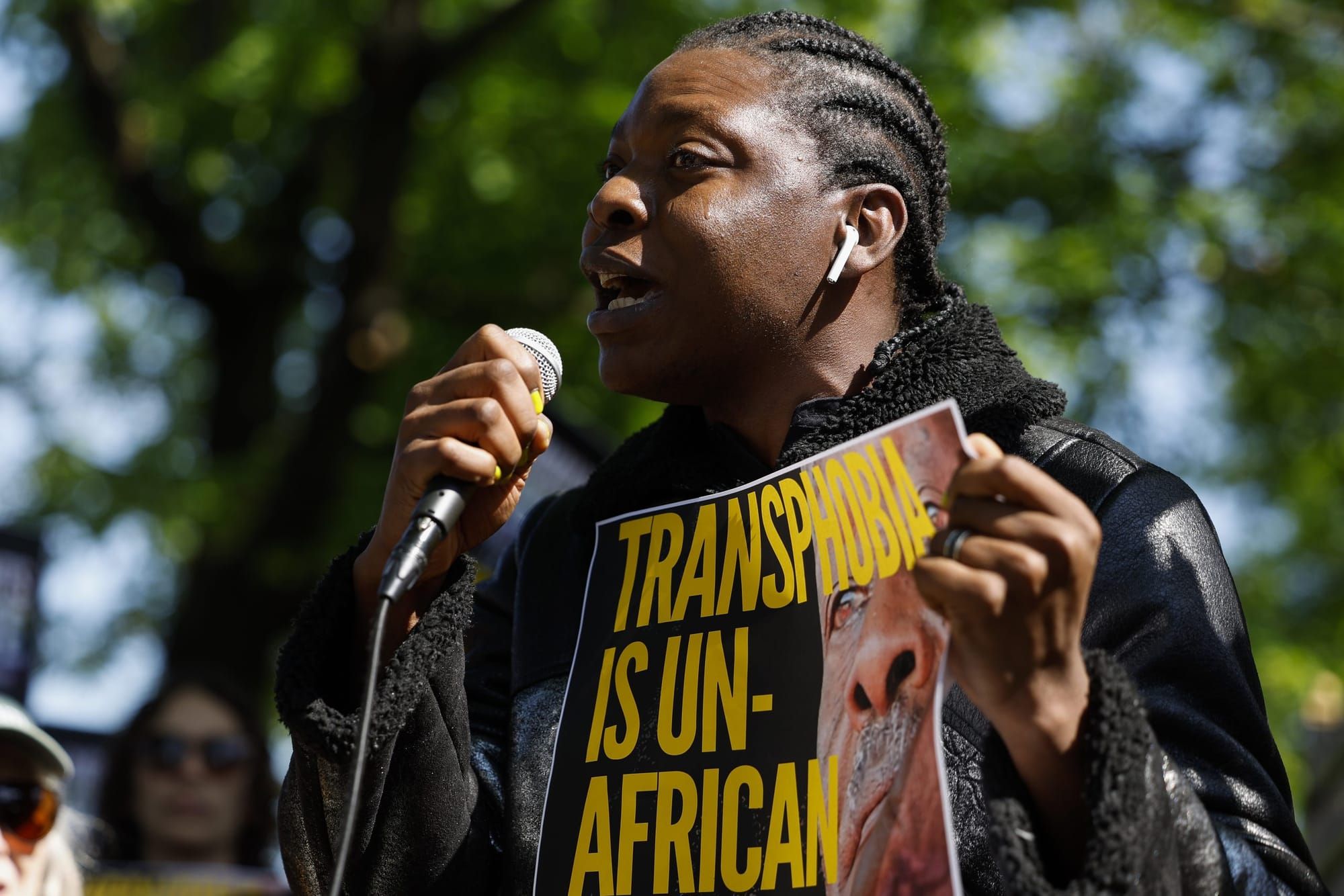 color photograph of a Black masc person holding up a sign that reads "Transphobia is un-African"