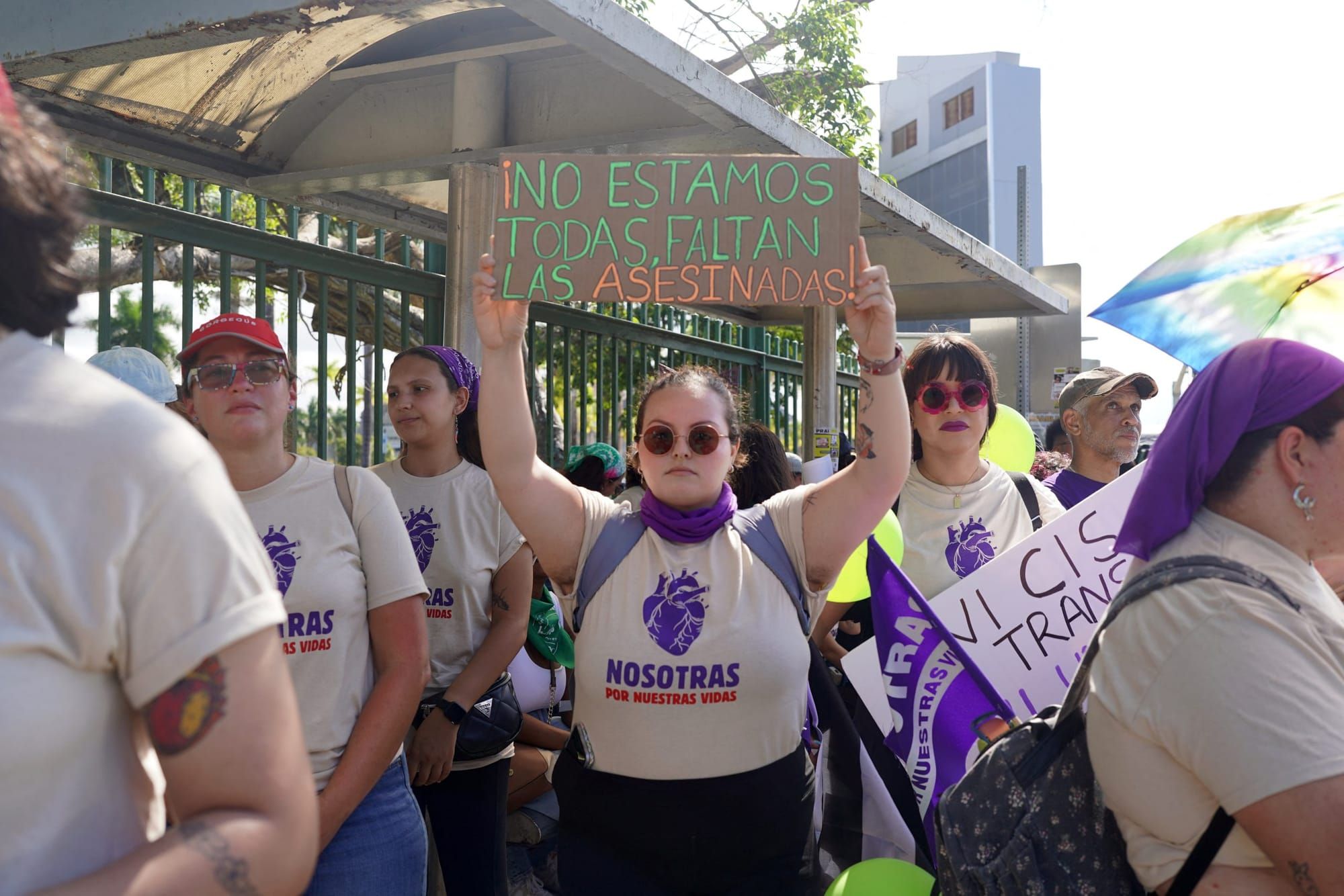 color photograph of an outdoor protest in support of women's rights. a woman in a white T-shirt holds up a sign that reads "n