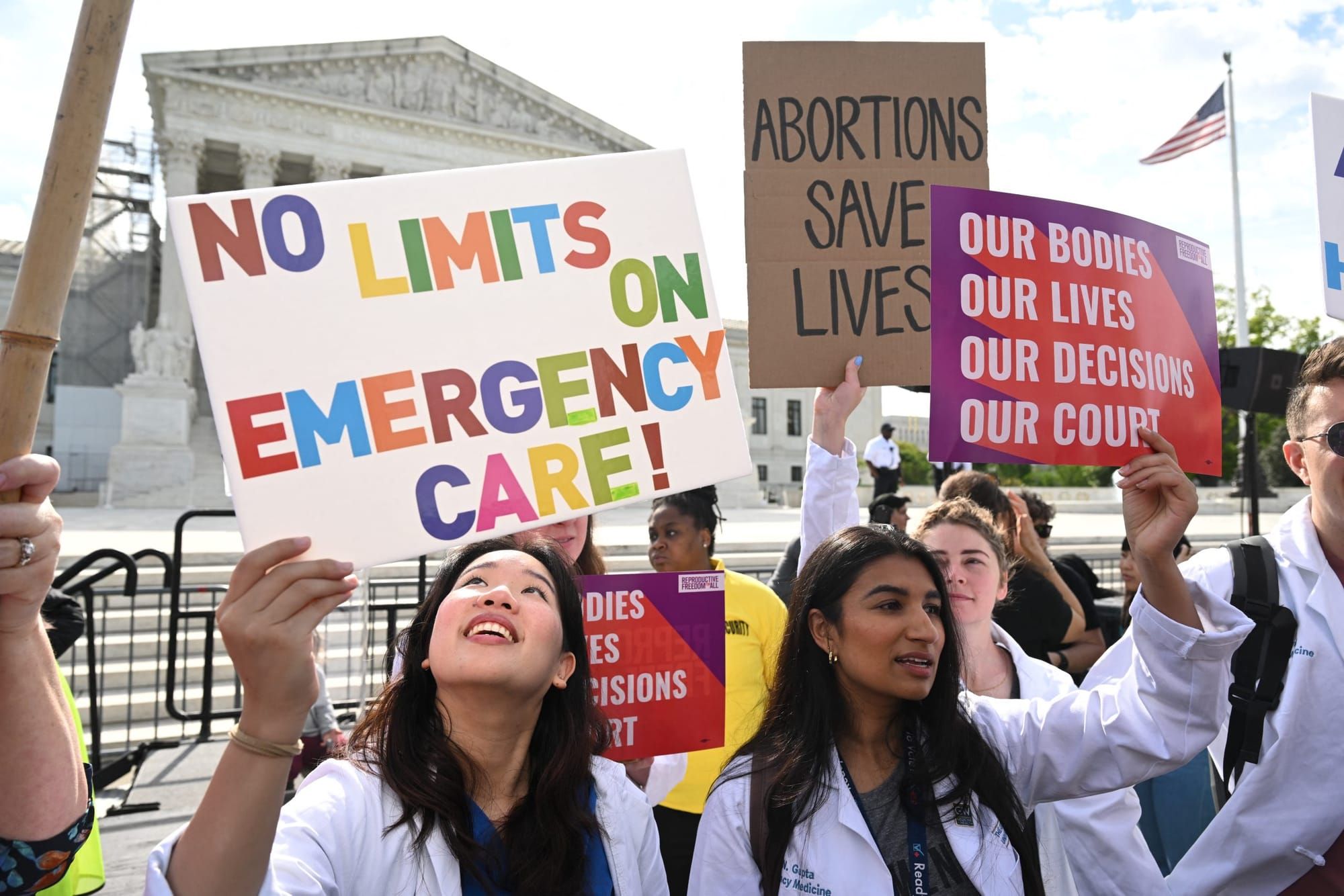 color photograph of an outdoor protest in support of abortion access. in the foreground people hold signs that read "no limit