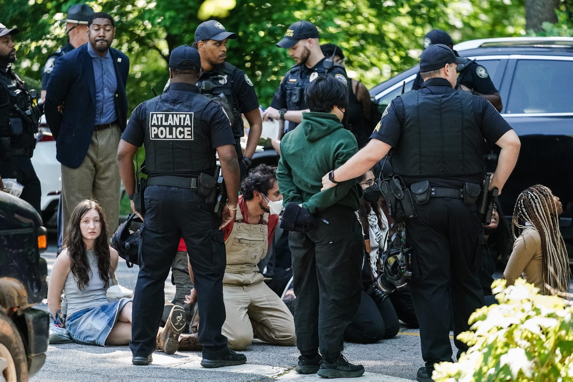 color photograph of several police standing around a person with their hands behind their back