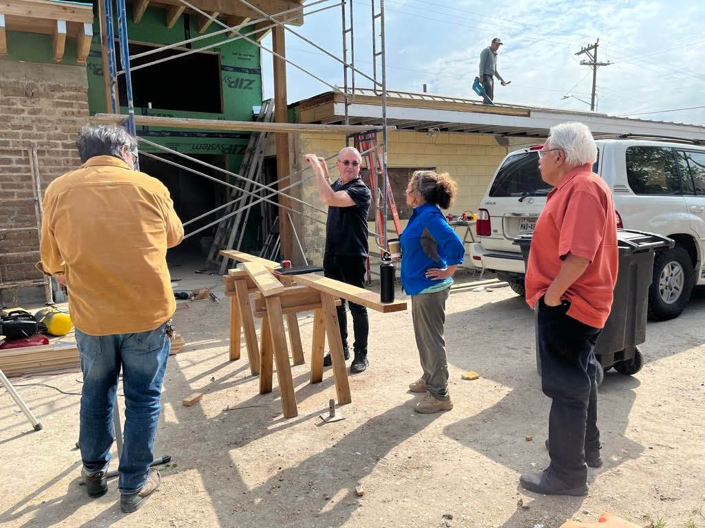 color photograph of four people standing outside of a building under construction