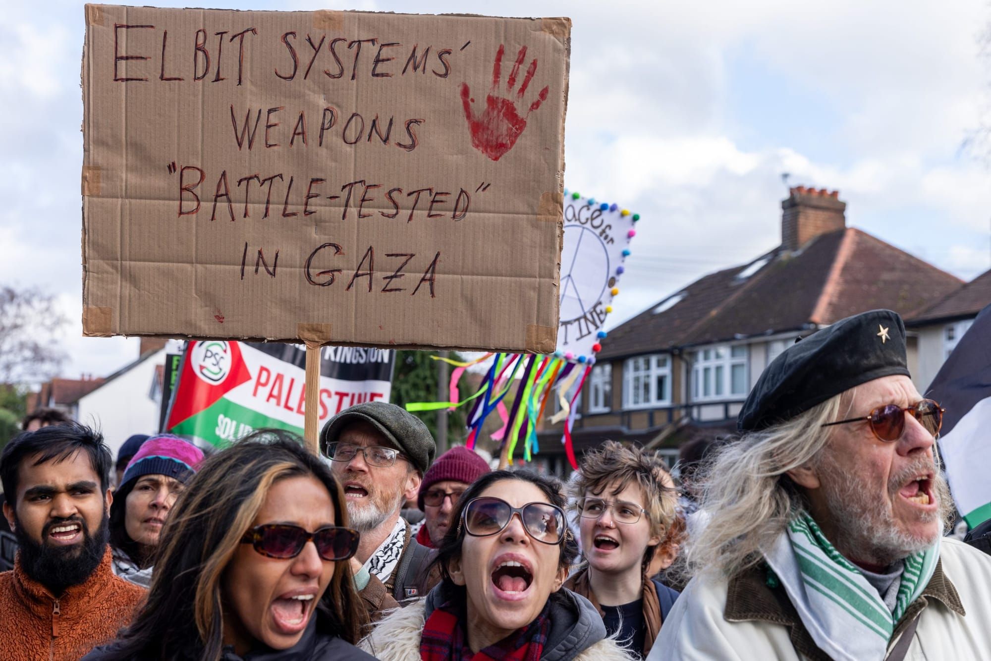 color photograph of an outdoor protest in support of palestinian liberation. in the mid-ground, someone holds a cardboard pos