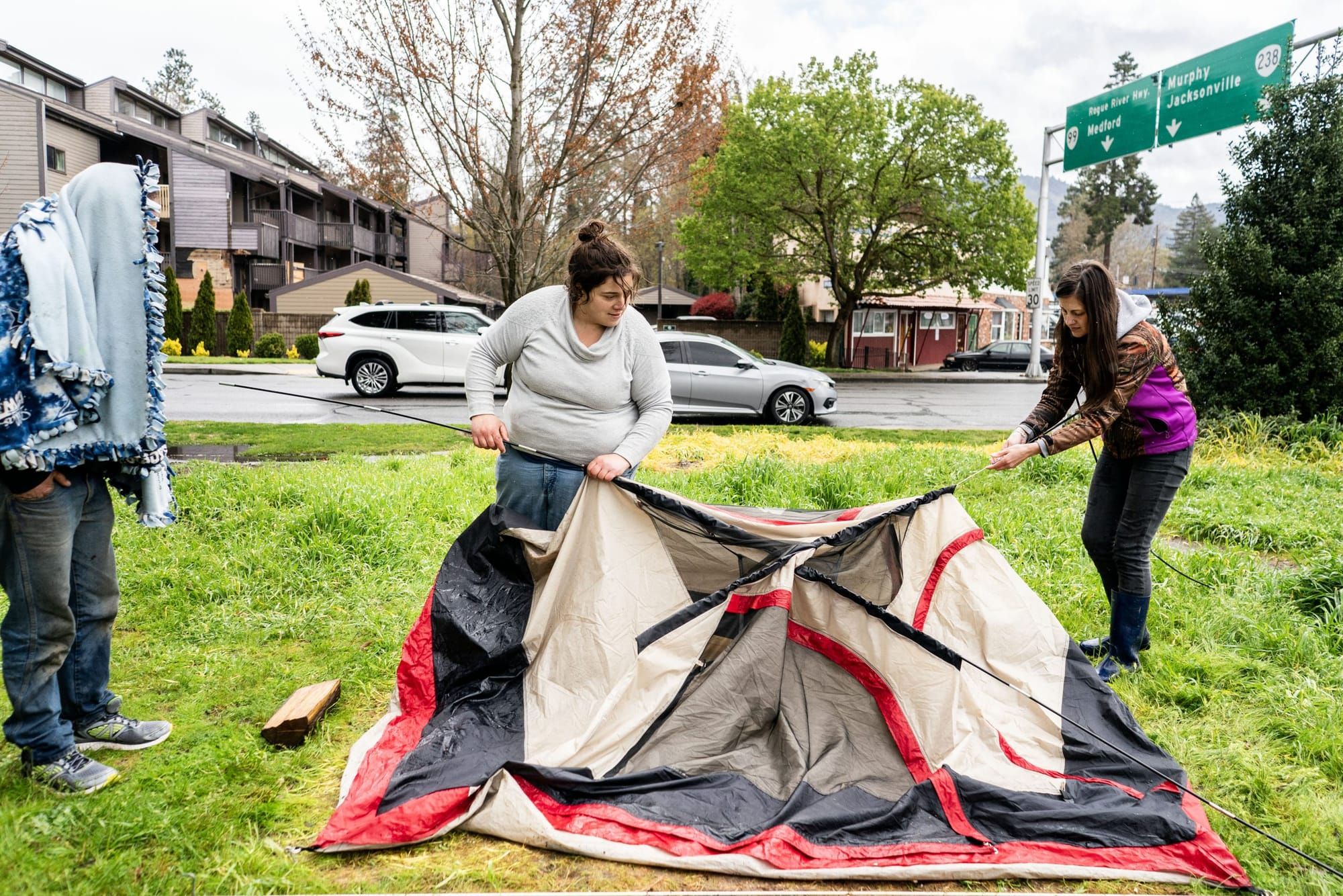 color photograph of two people taking down a tent in a park
