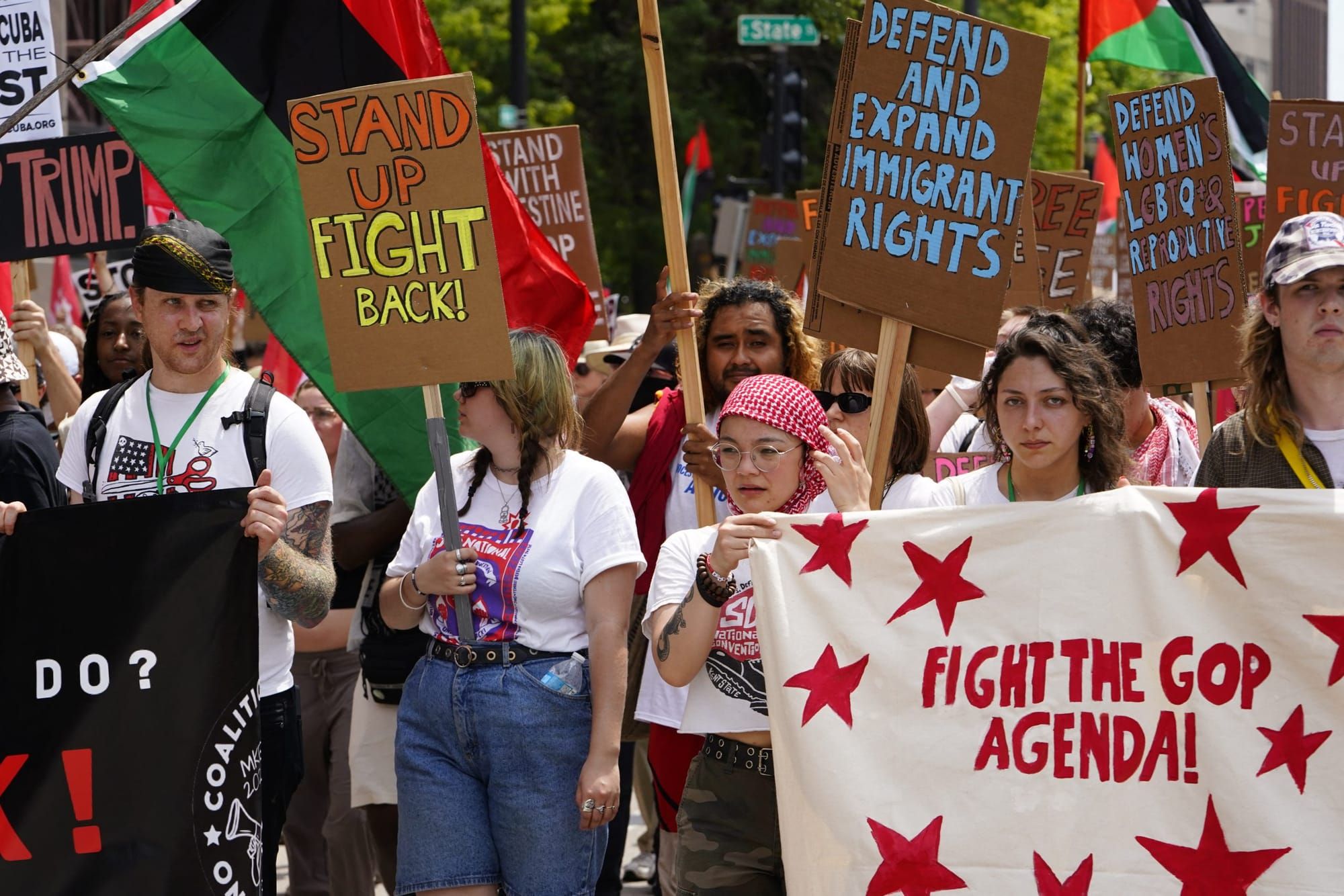 color photograph of an outdoor protest against the Republican National Convention. People hold up banners that read "fight th