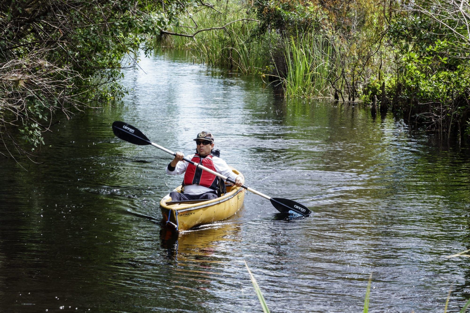 color photograph of a man paddling a canoe down a river