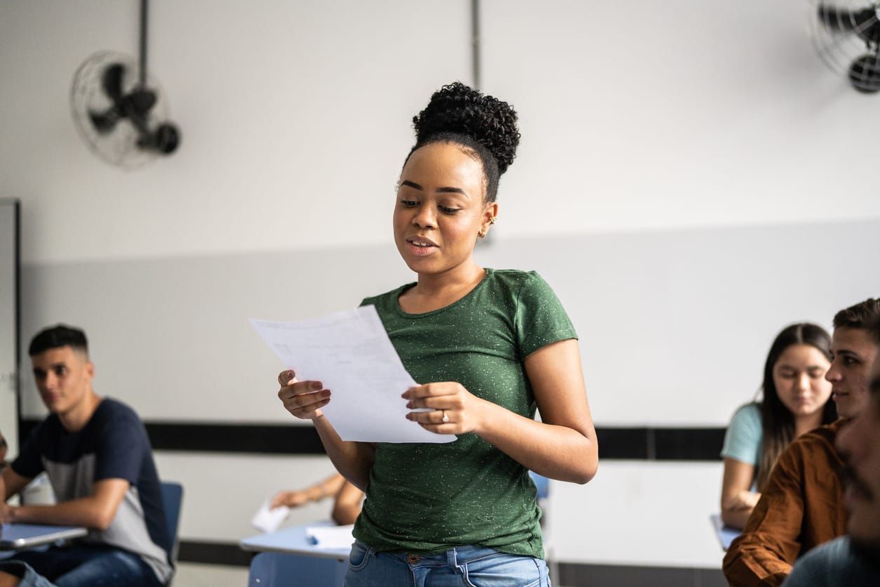color photograph of a young Black teeange student reading aloud in the classroom
