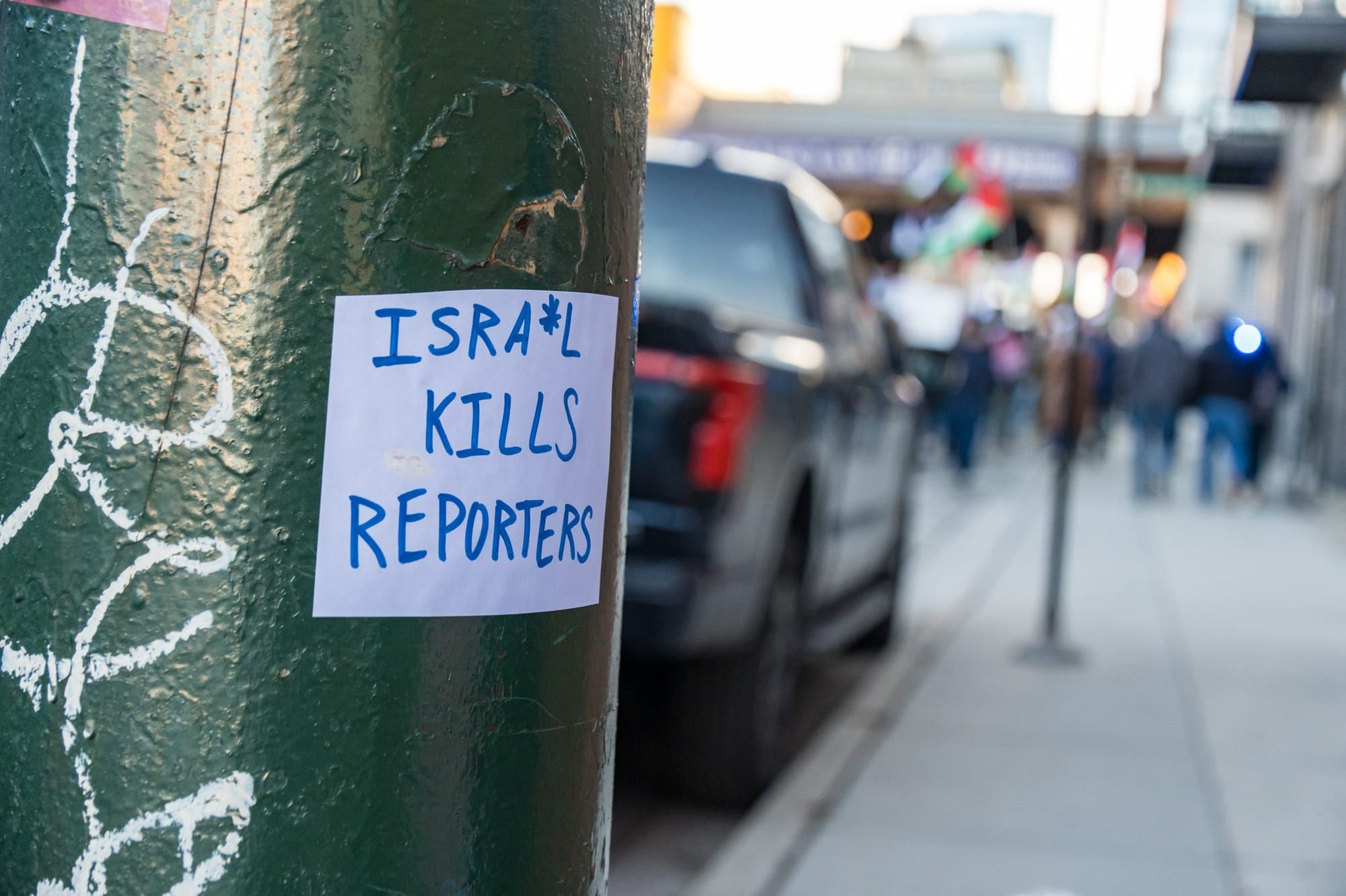 photograph of phone poll with a handwritten sign that reads "Isra*l kills reporters"