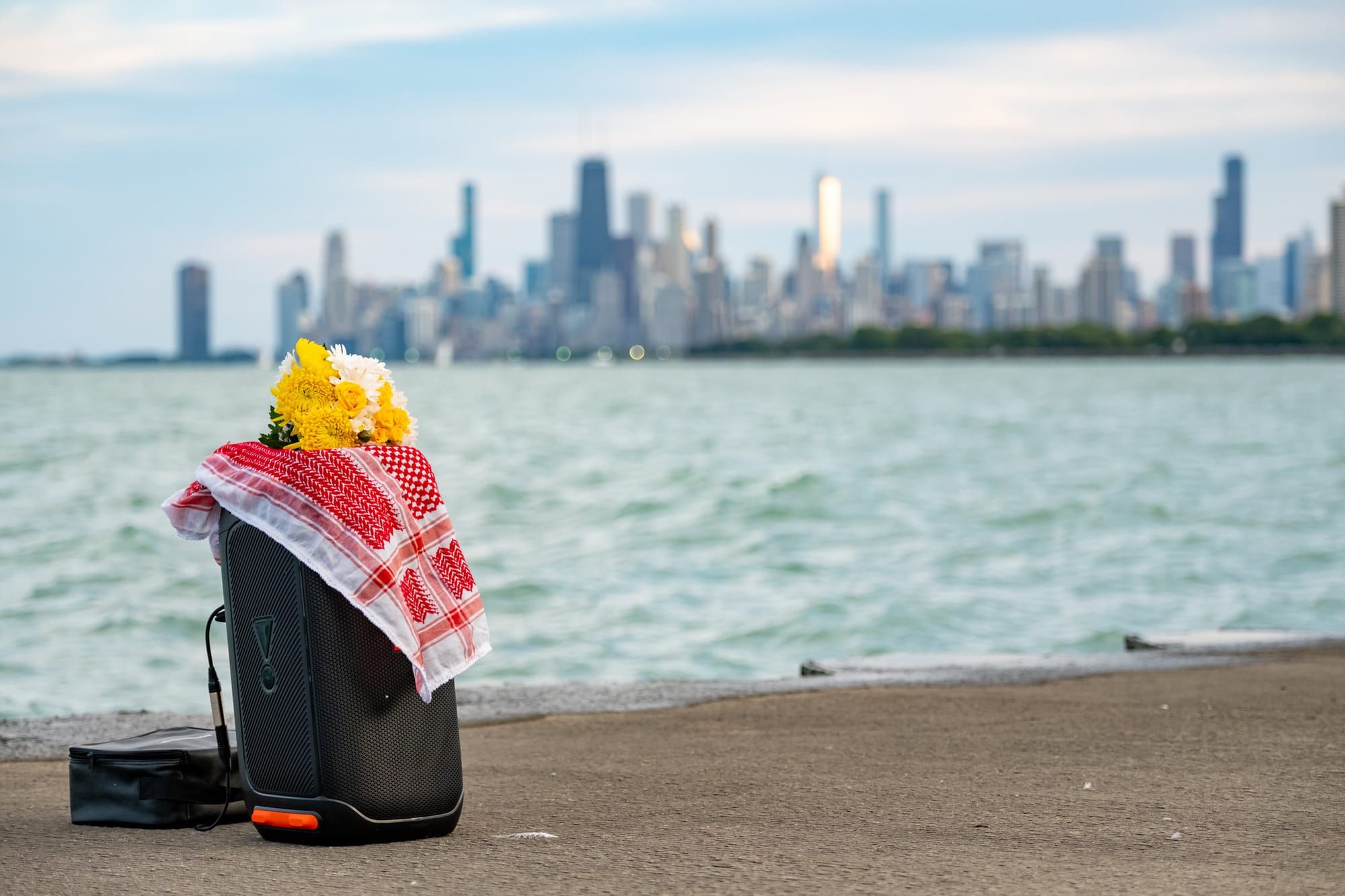 A keffiyeh and yellow flowers sit on top of a black camera bag.