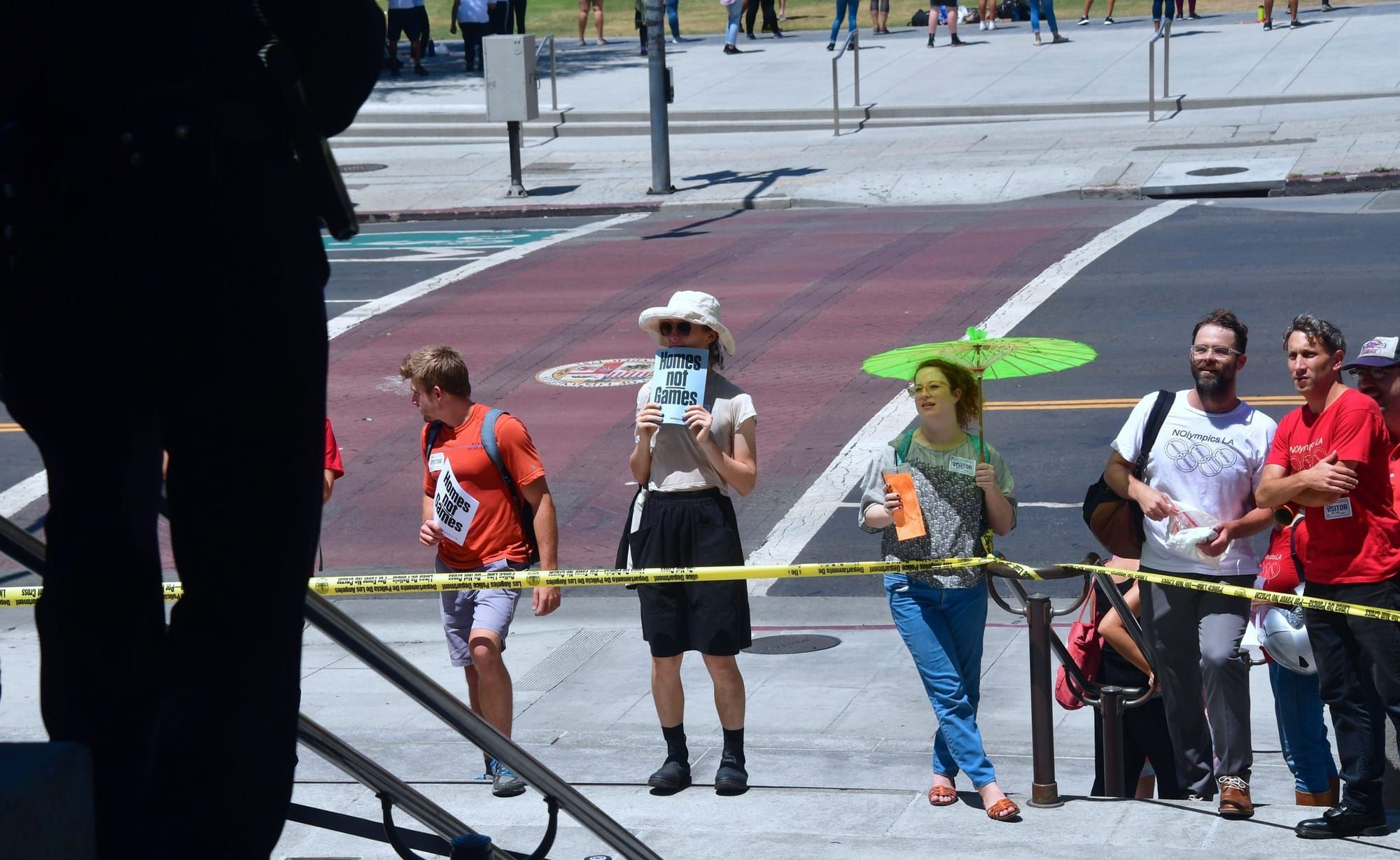 A small group of protesters stand on the steps of City Hall with caution tape strung