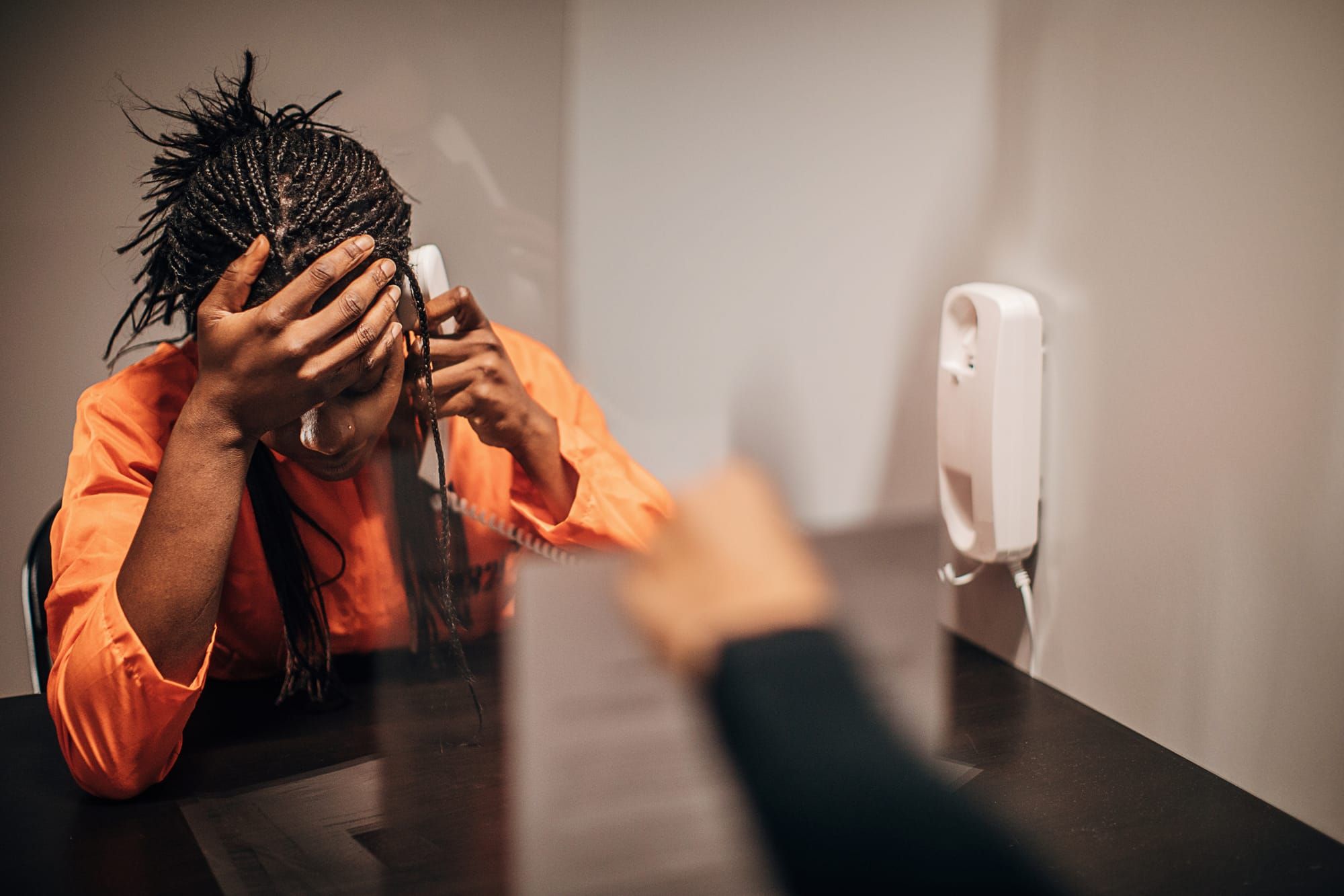 Inmate holds hand on her head while talking on the phone to her attorney.