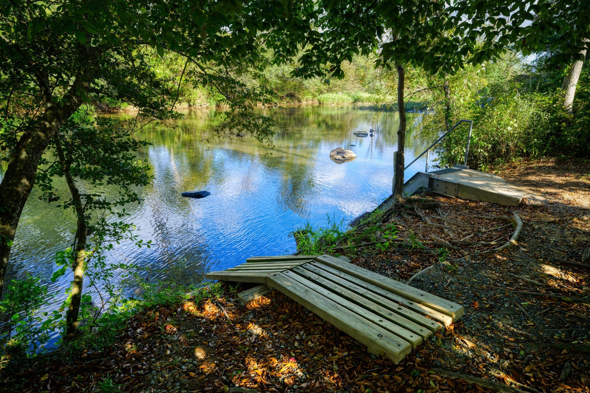 A shadowy outdoor landscape of a canoe boat launch on the southern Haw River in North Carolina.