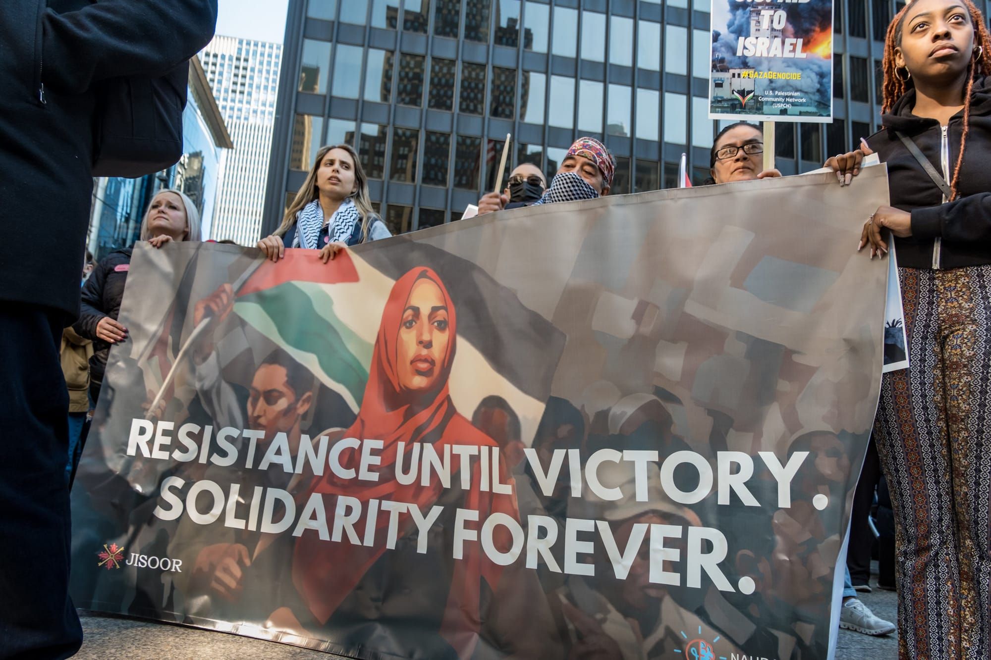 A protest banner reads, "Resistance until victory. Solidarity forever."