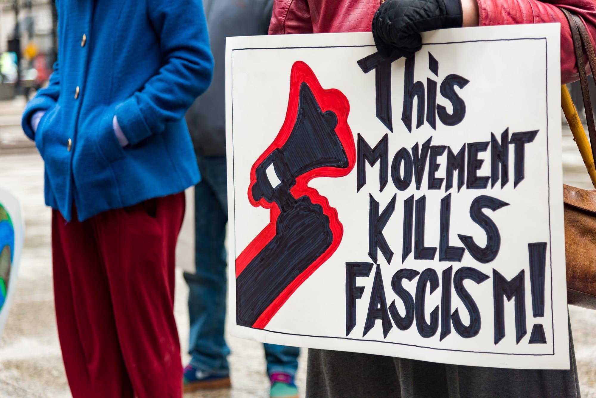 A protester holds a sign that says, "This movement kills fascism."