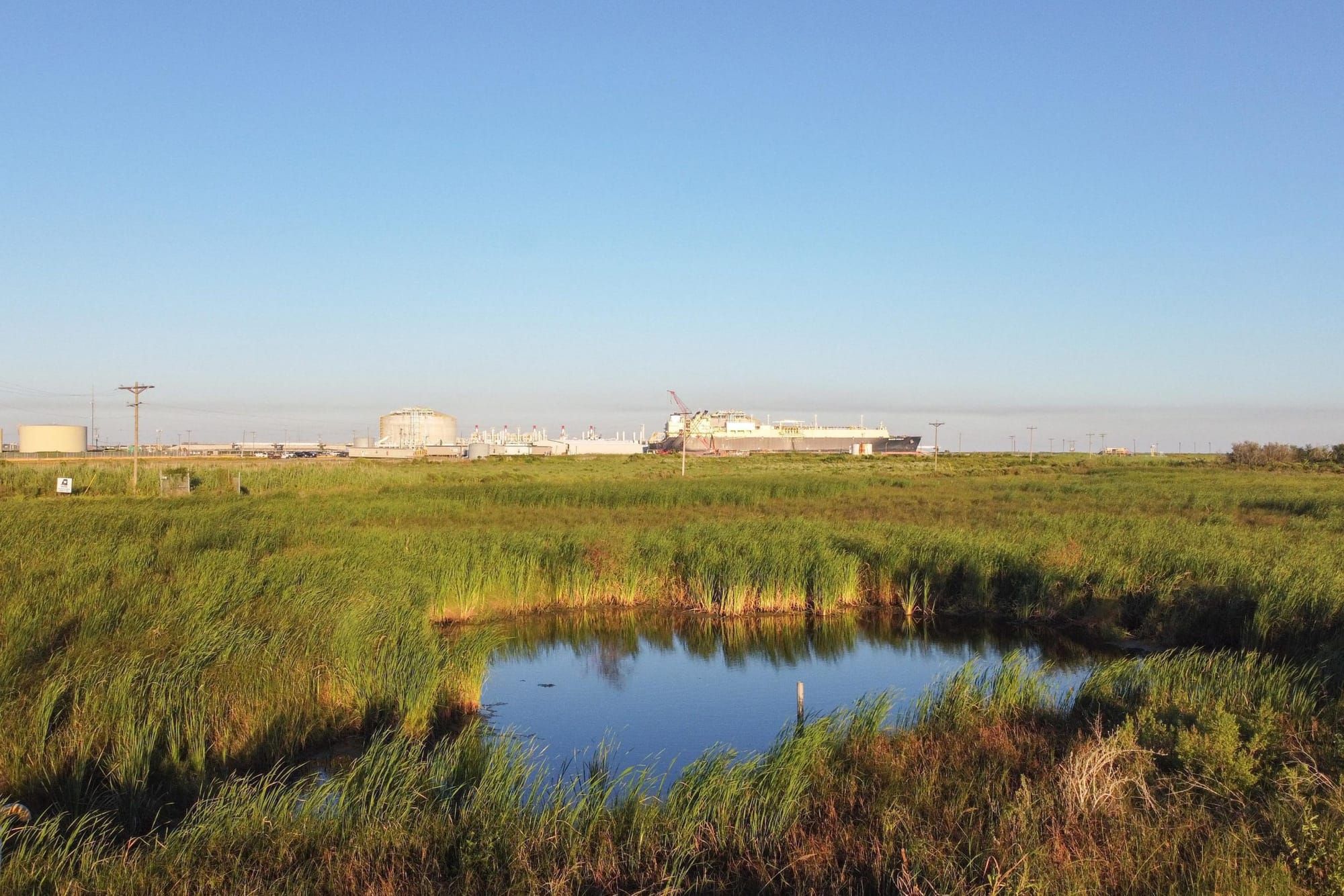 LNG plant in Louisiana in the distance, with wetlands in the foreground