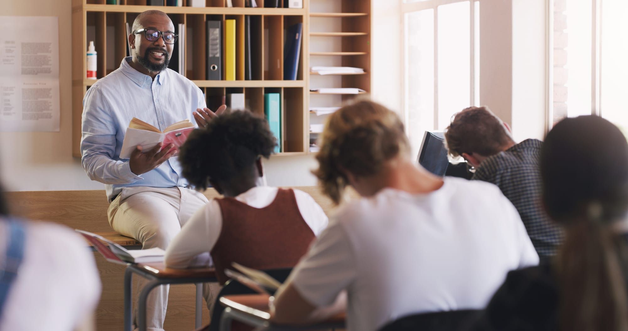 Teacher reading a book to his students in a classroom
