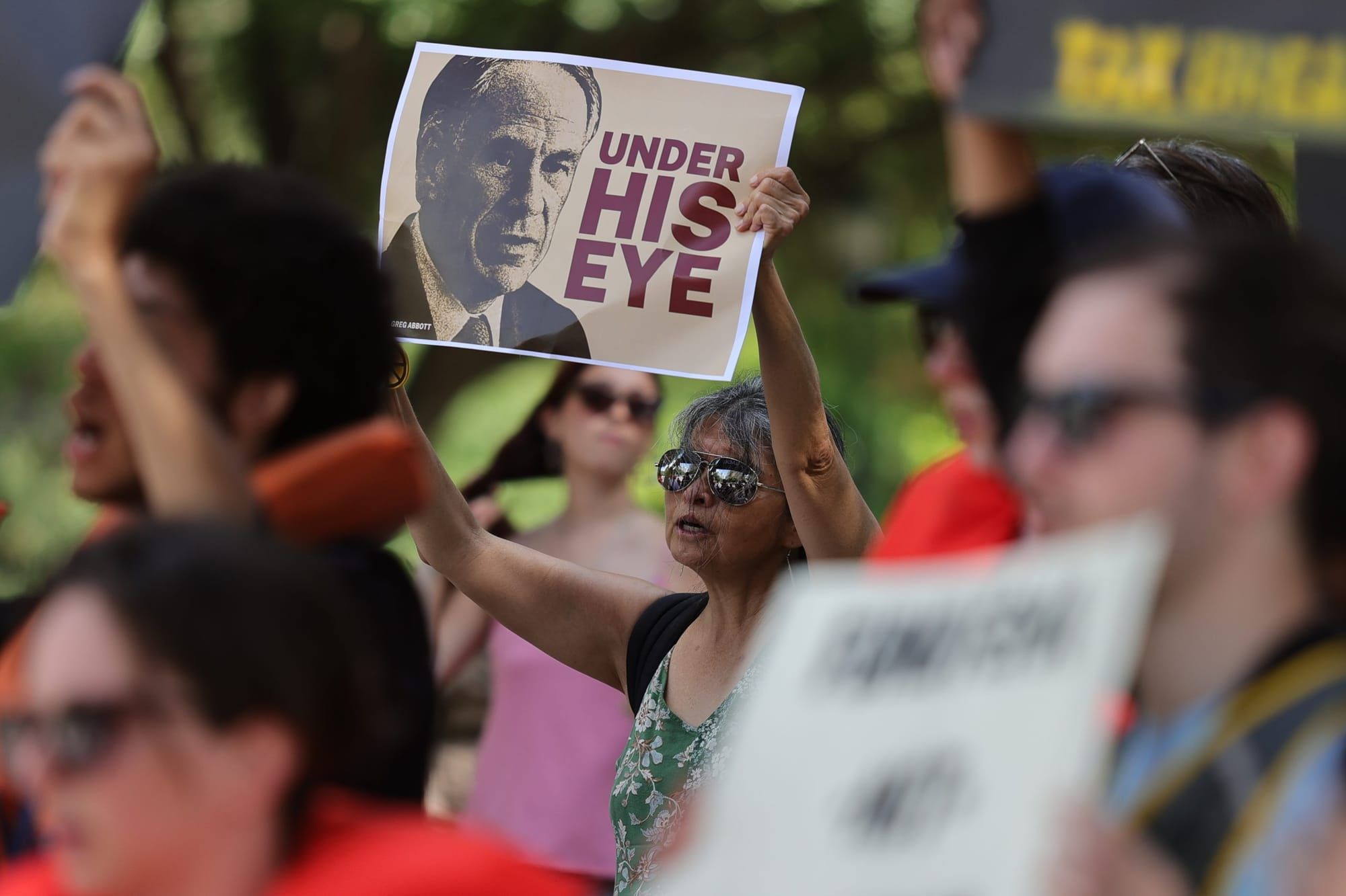 A protestor holds a sign depicting the Texas state governor with the words, ''under his eye.''