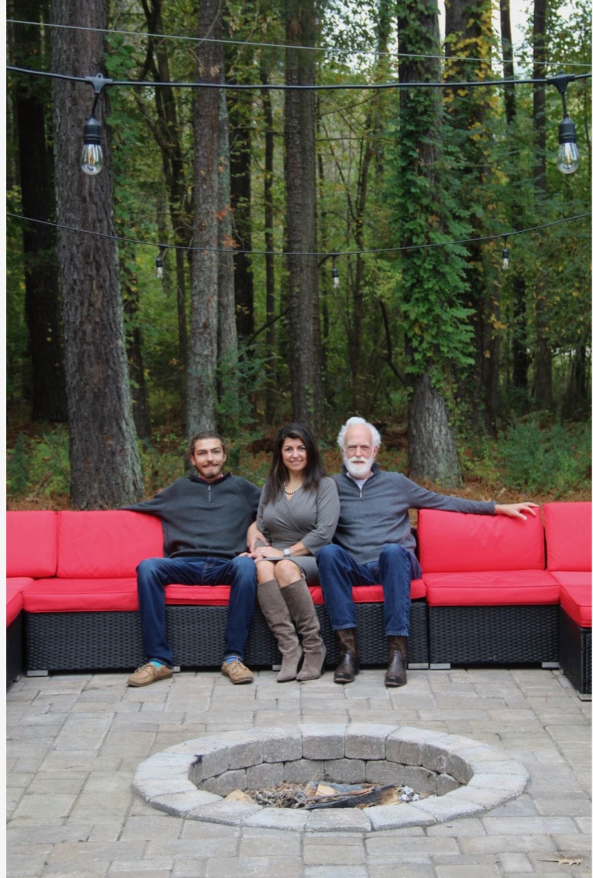 Charlie, Rachelle and Phil seated together beside their woodland fire pit