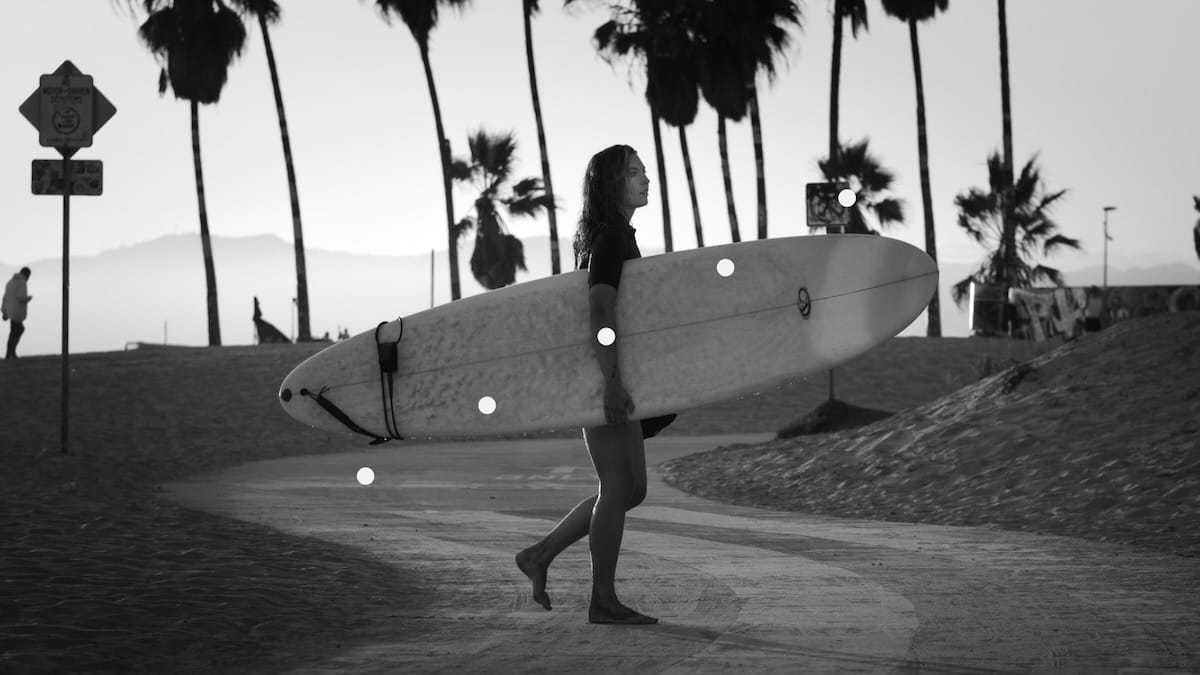 A surfer carries her surfboard in Venice Beach, California
