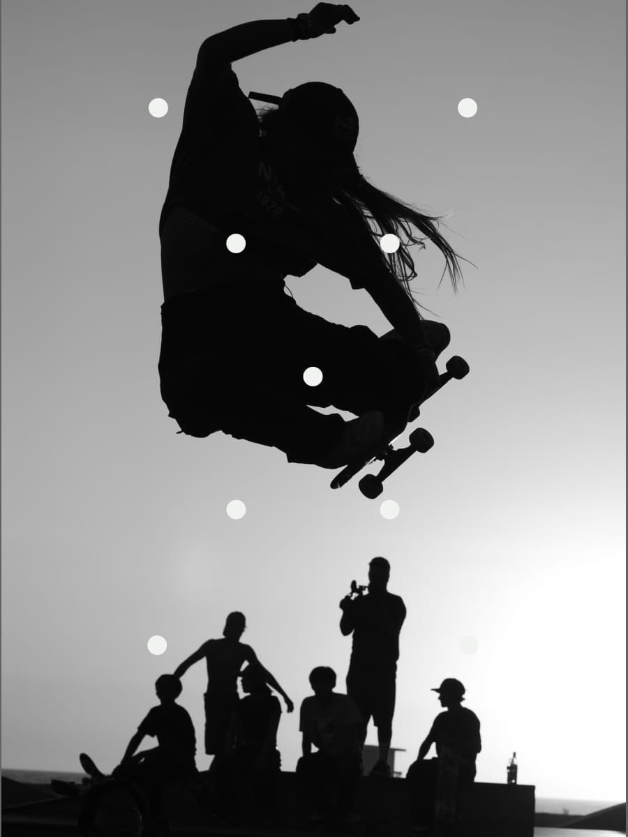 A silhouetted skateboarder leaps over other silhouetted figures