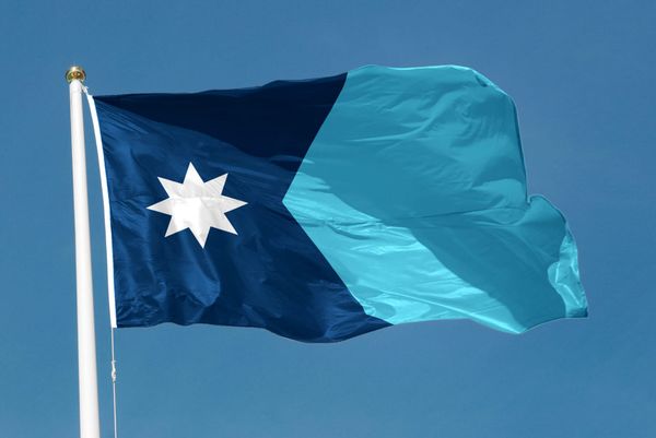The Minnesota state flag waves against a blue sky.