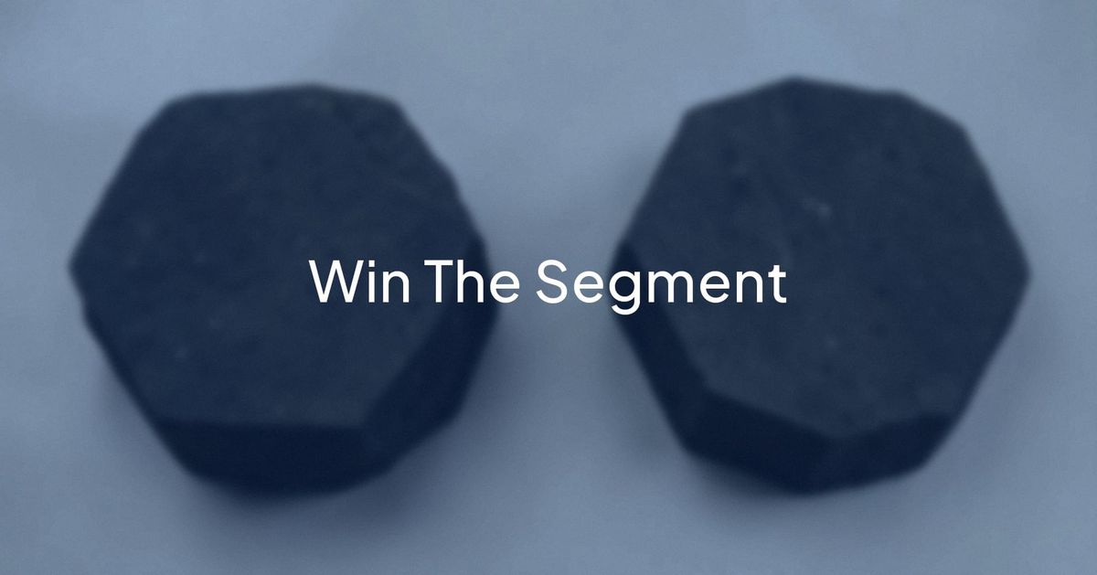 Two dark hexagonal basalt columns against a pale sky, with the words Win The Segment