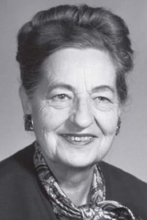 A black-and-white studio portrait of an older woman smiling warmly at the camera.