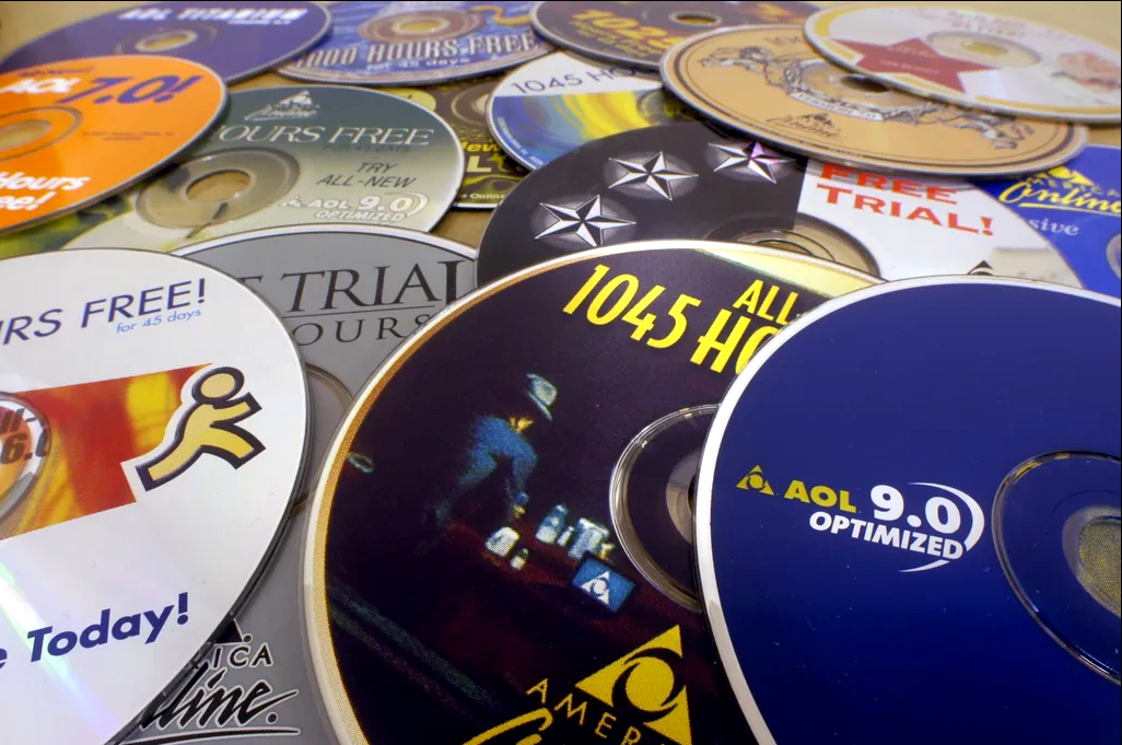 Many overlapping AOL CDs overlapping on a table. They are all different colors but they all say AOL on them.