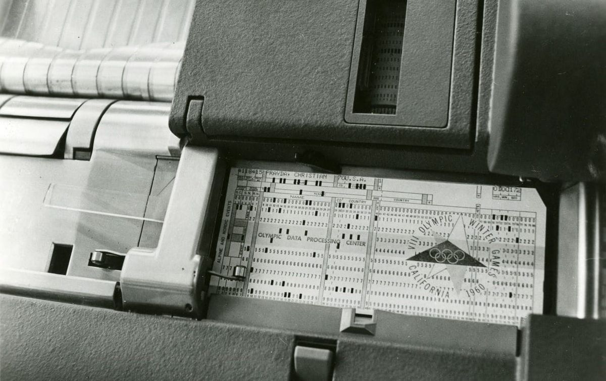 A black-and-white photo of a punched card resting in the feed tray of a card-processing machine.