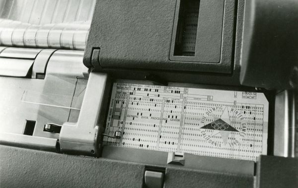 A black-and-white photo of a punched card resting in the feed tray of a card-processing machine.
