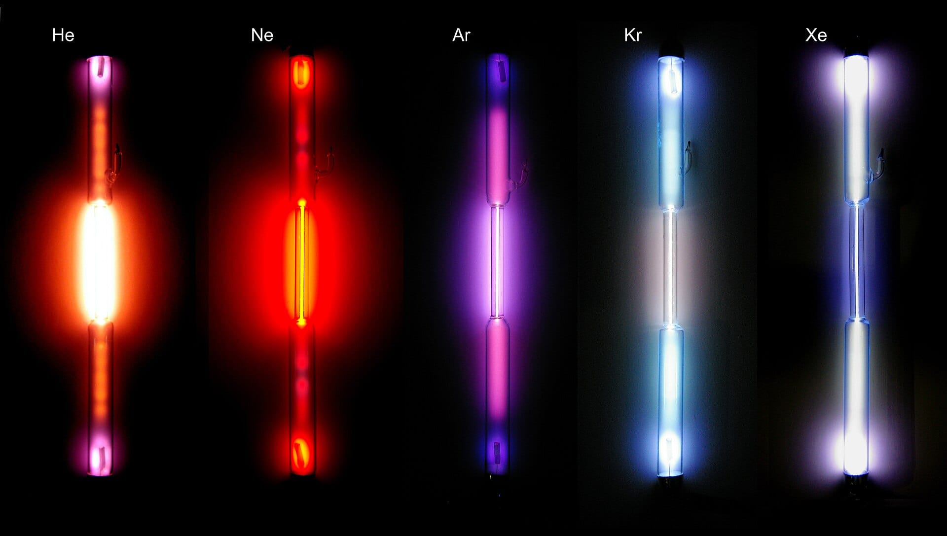 Five intensely glowing tubes of Helium, Neon, Argon, Krypton, and Xenon, against a black background.
