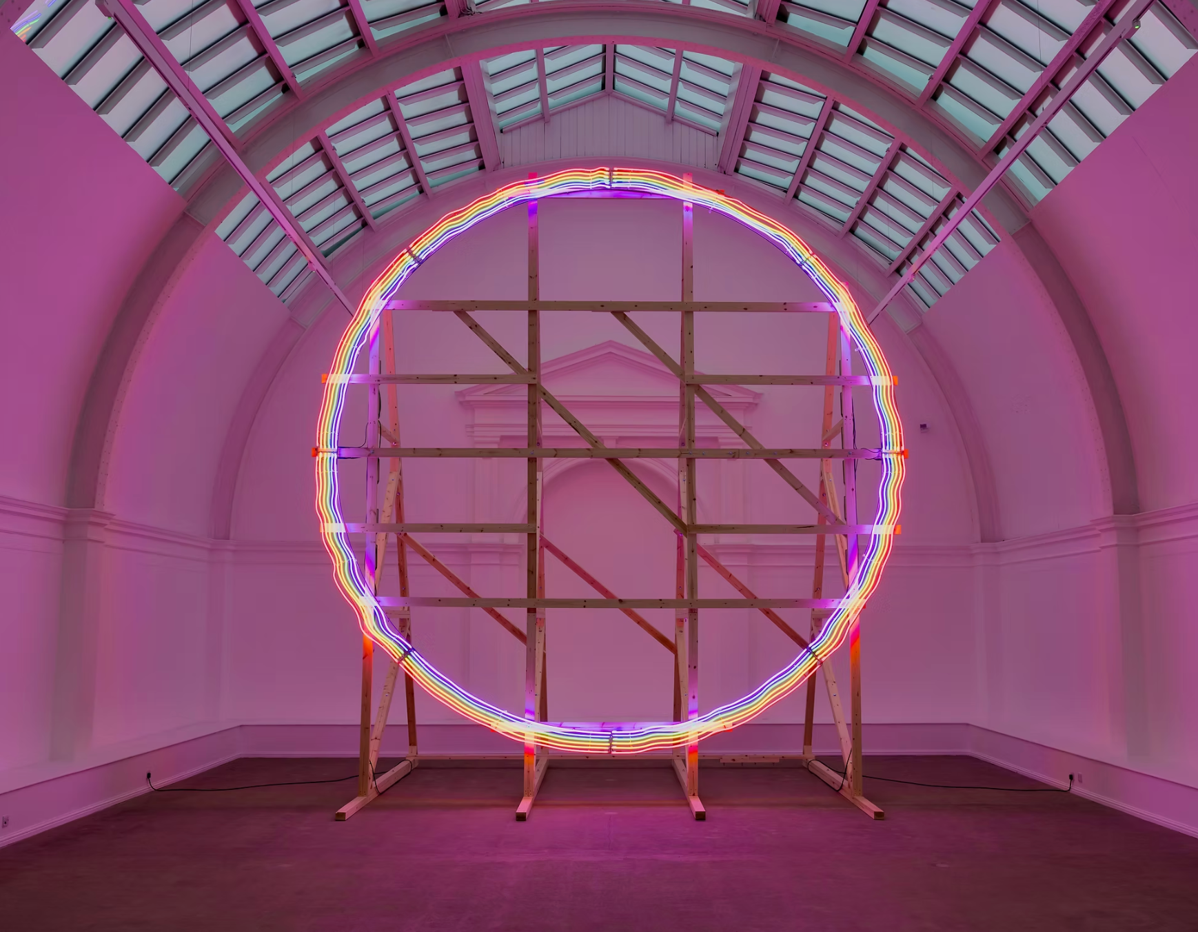 A huge neon work by Richard William Wheater in an arched room in Leeds Art Gallery. It's a huge, fine circle of neon in rainbow colours, awash in pink light.