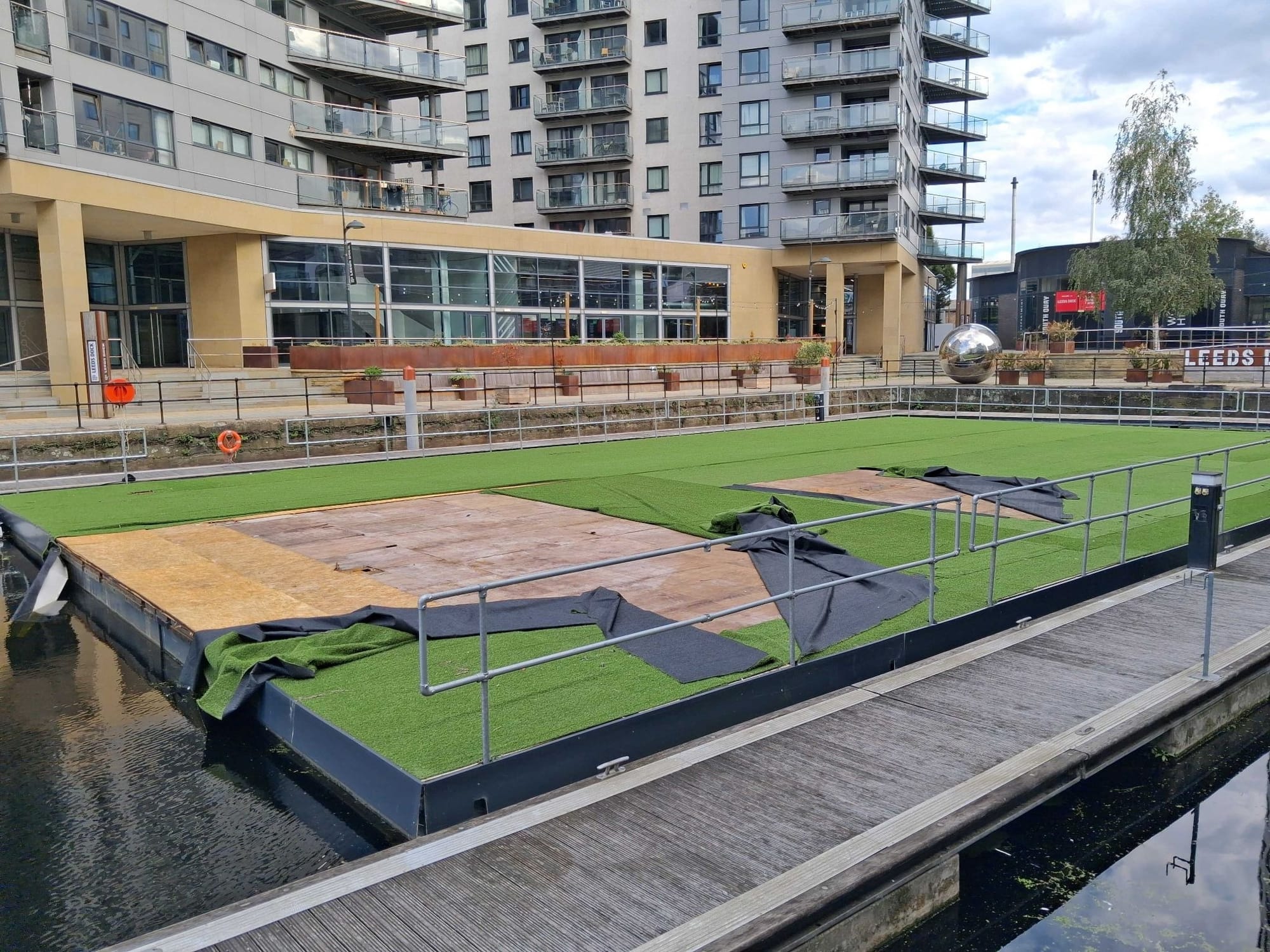 A huge, unused pontoon covered in dilapidated green astroturf at Leeds Dock.