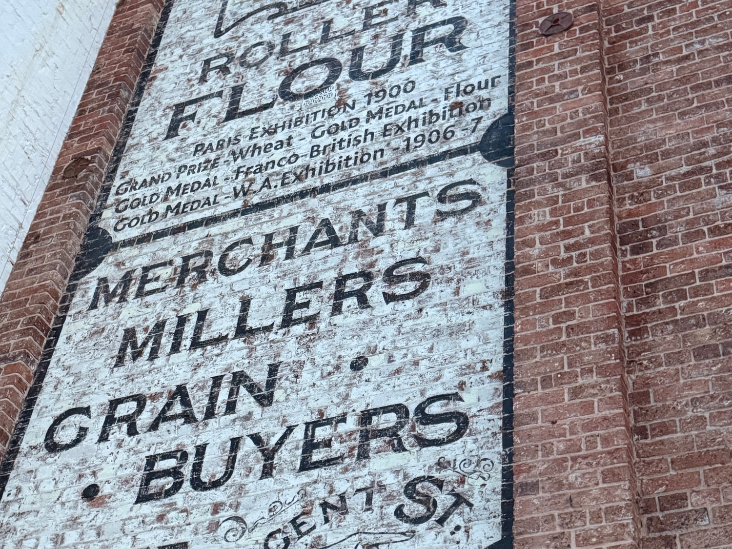 The faded painted Premier Roller Flour sign on the brick wall of the old mill.