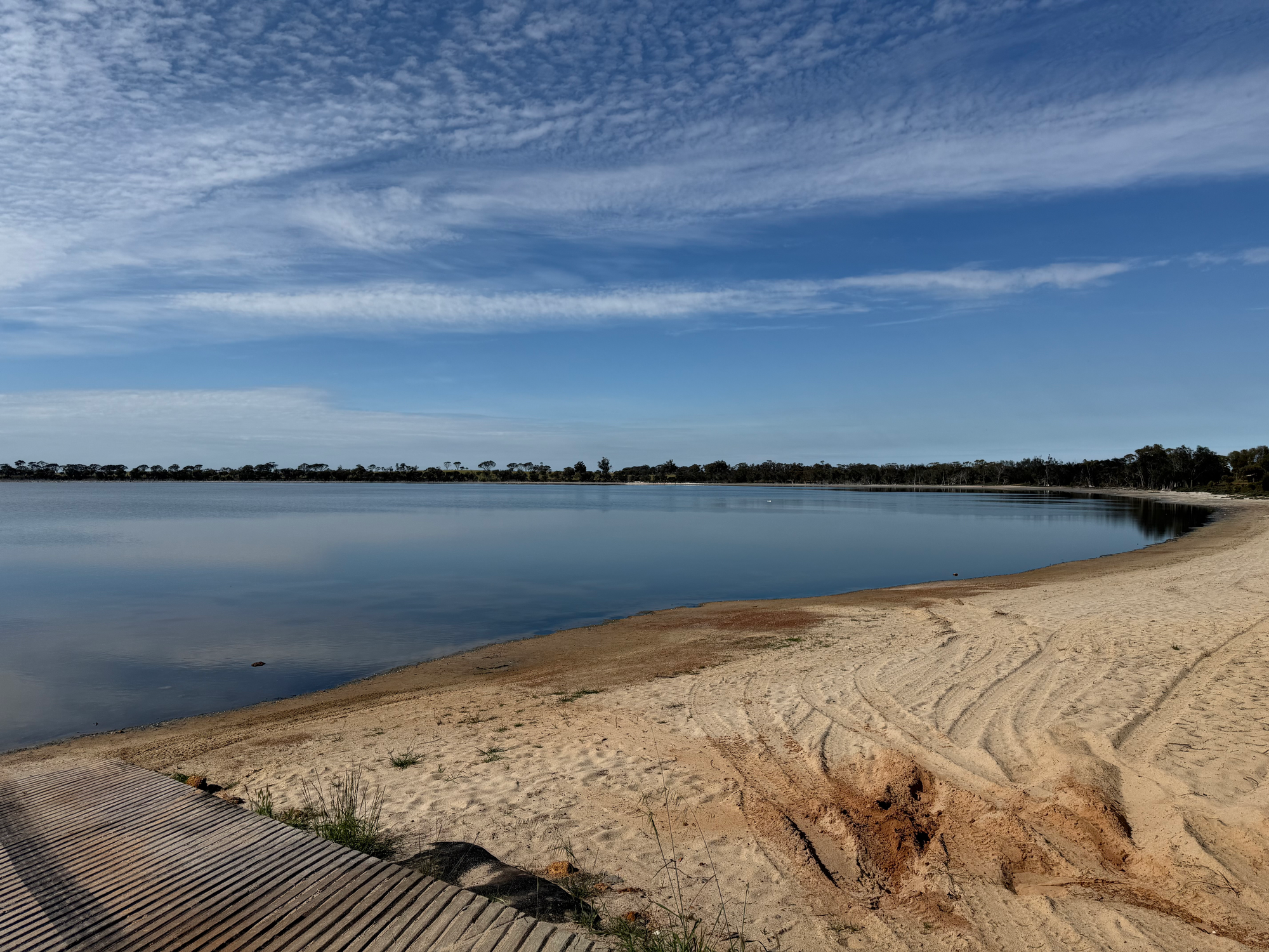 Lake Ewlyamartup, still water and a sandy shore under thin cloud.