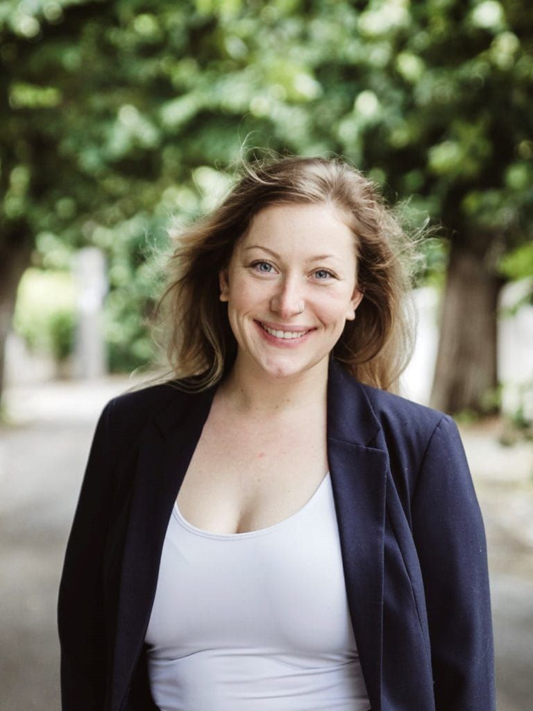 Maile Grace, a calming and compassionate parent coach, smiling softly in a peaceful, neutral space.