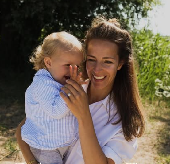 Melanie von Muhlen, parenting coach, smiling warmly while holding a baby