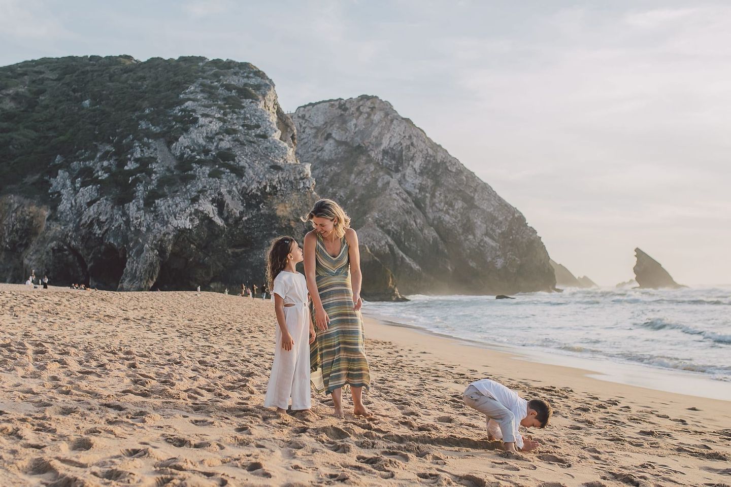 Mother and two young children on a beach at sunset in Portugal, symbolizing mindful parenting, connection, and the heart behind 15 Summers.