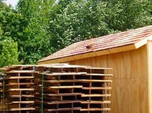 Outdoor structure-protection materials test: stacked wood cribs staged against the roof deck of a test structure, from the Forest Service San Dimas evaluation.