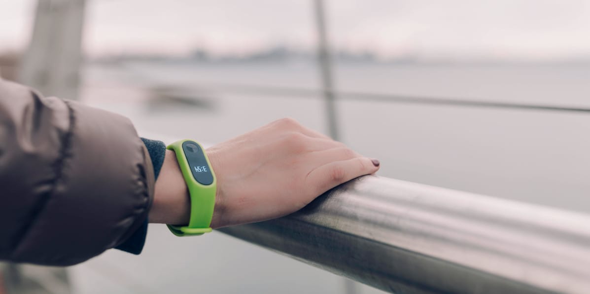 Close-up of a hand with a fitness tracker touching a handrail.
