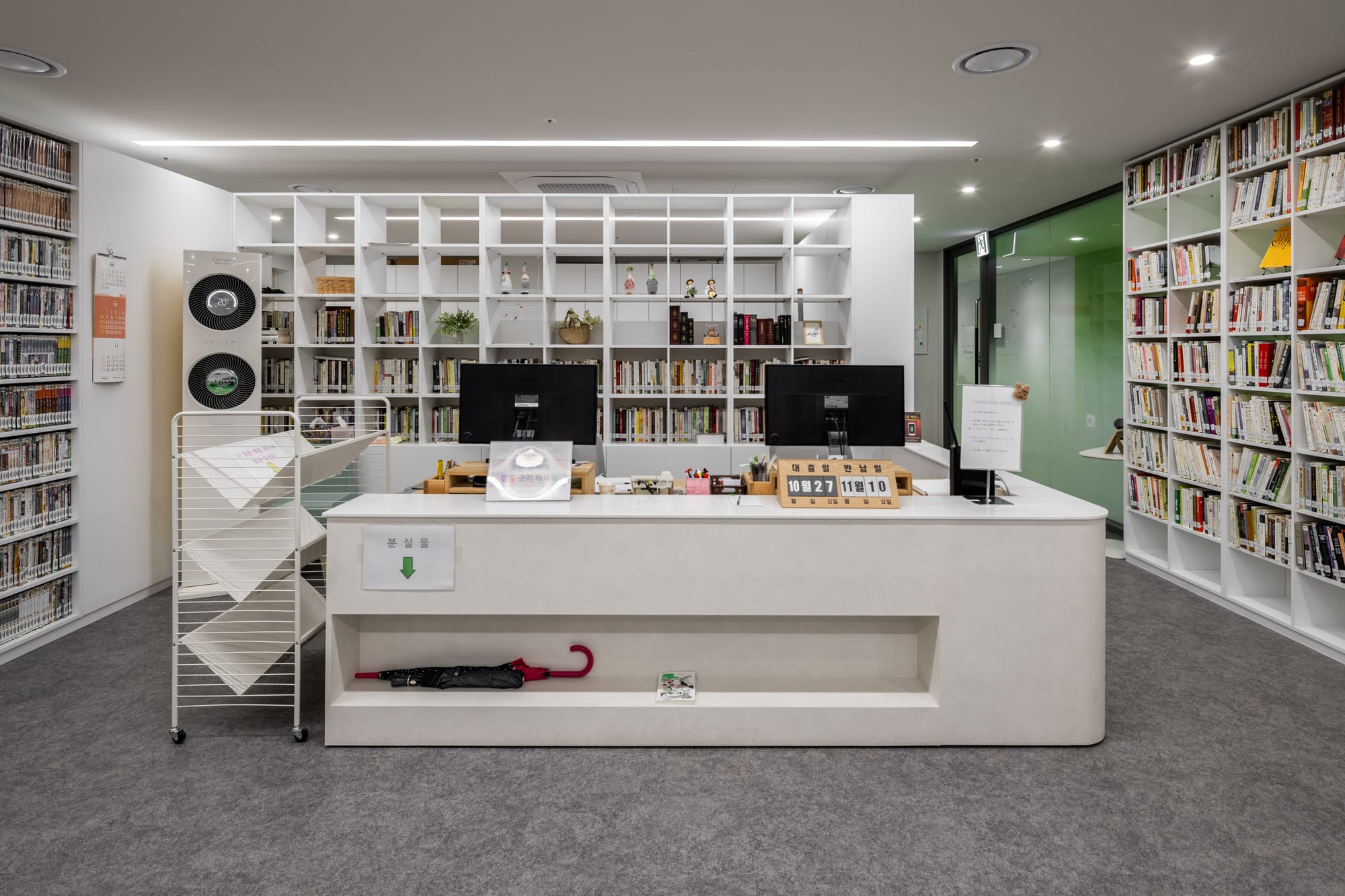 Modern library checkout counter inside Onnuri Church Youth Center and Seoul Providence School, with organized bookshelves and clean interior design