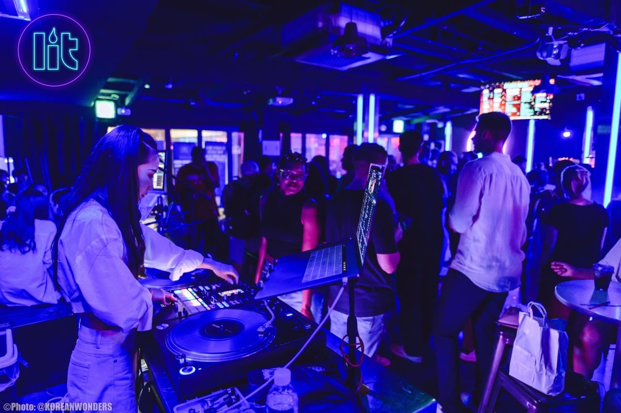 Female DJ spinning live at Lit Lounge Itaewon with neon lights and crowd dancing during a Seoul nightlife weekend party