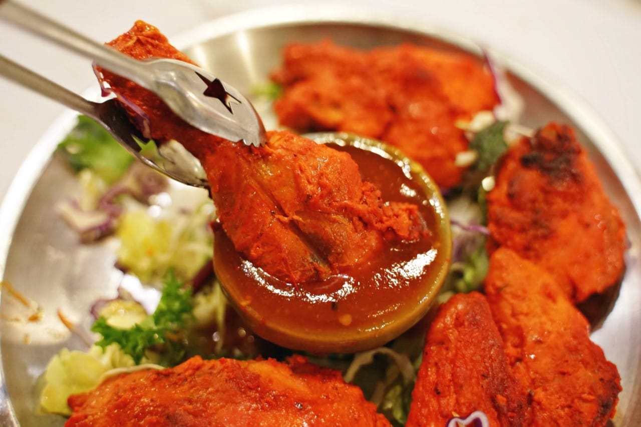 Close-up of juicy chicken tikka served with sauce and fresh vegetables at New Saladin Dongseongno Indian restaurant in Daegu