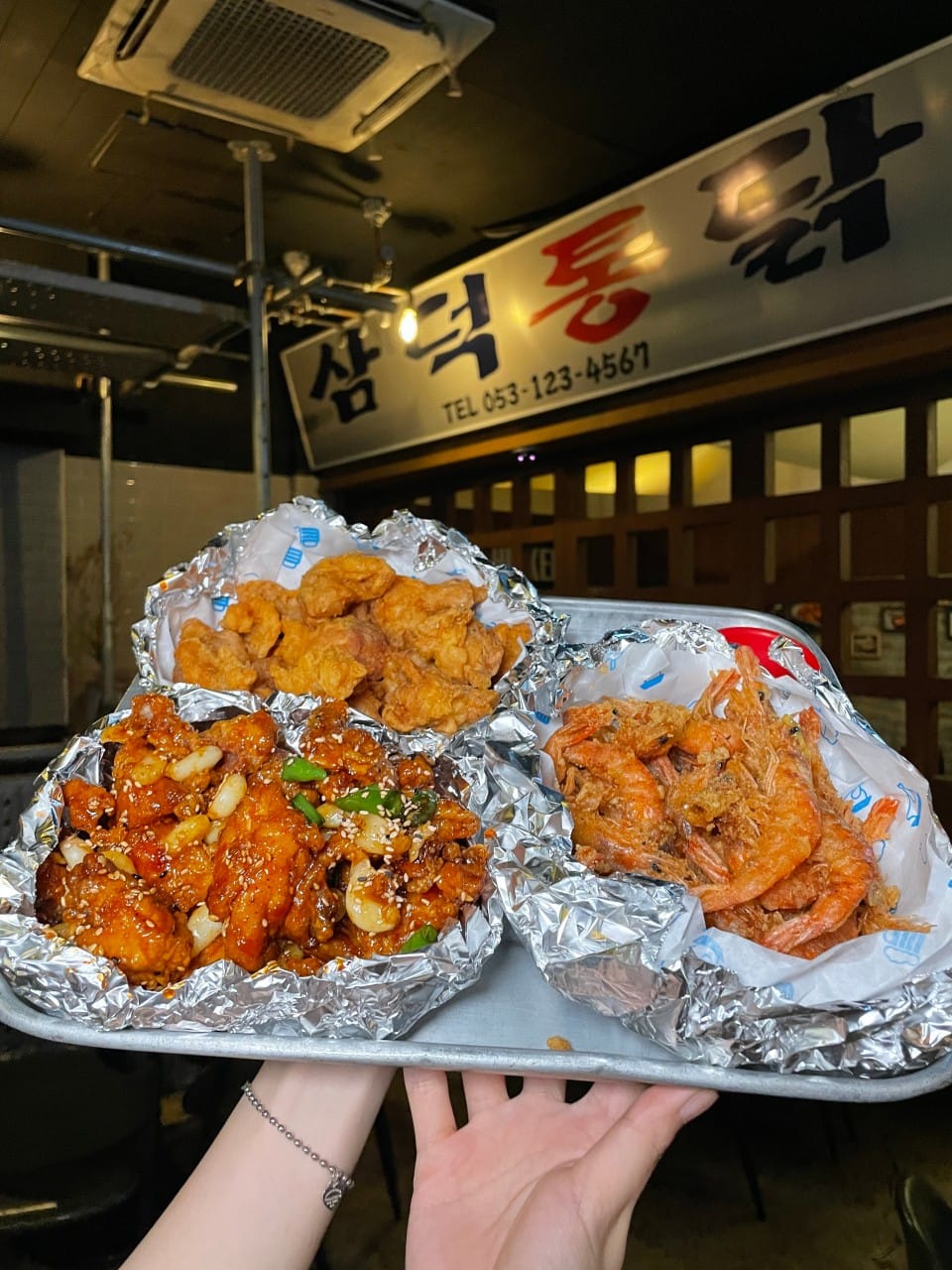 Tray of Korean fried chicken and shrimp at Samdeok Tongdak in Daegu with restaurant signage in background