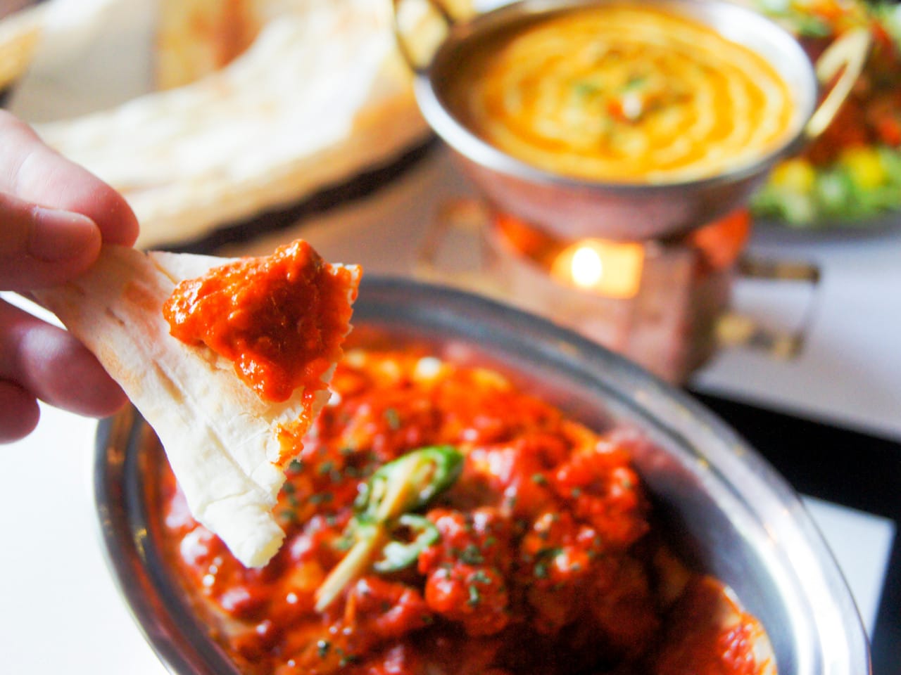 Close-up of butter chicken on naan at Taj Mahal Indian restaurant in Daegu, Korea, with dal curry and salad in background