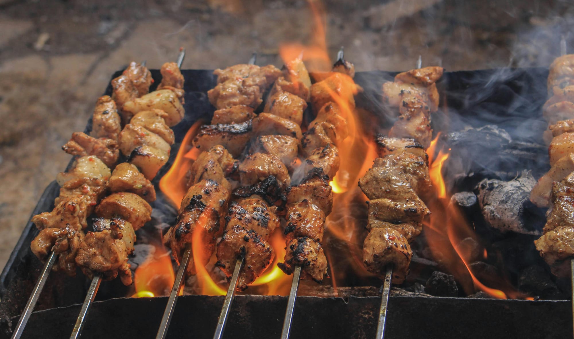 Tandoori chicken skewers grilling over open charcoal flames at an Indian restaurant in Korea