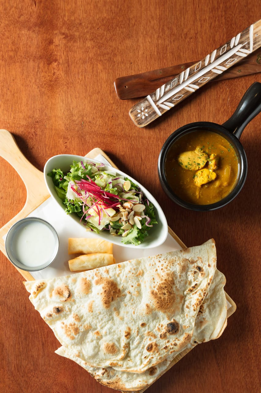 Way to India restaurant in Daegu serving chicken curry, naan bread, fresh salad, and yogurt dip on wooden platter