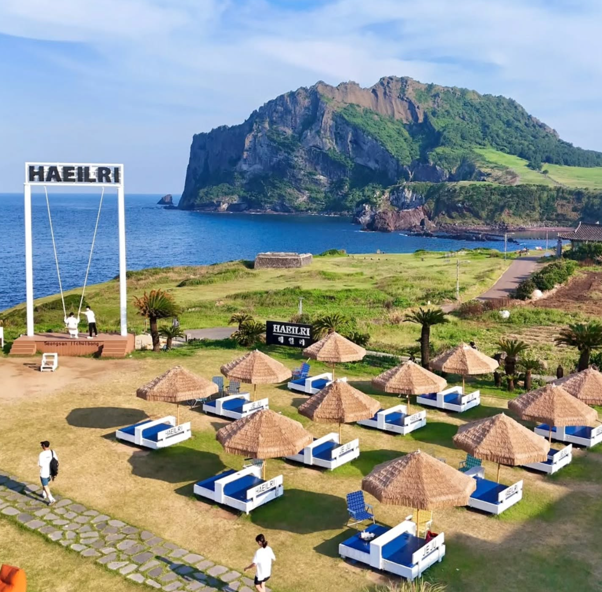 Haeilri Cafe with outdoor seating and giant swing overlooking Seongsan Ilchulbong in Jeju, a top stop for Jeju car rental travelers