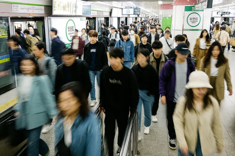 Commuters at Banwoldang Station platform in Daegu, South Korea, during rush hour with visible transfer signage for Line 1 and Line 2.