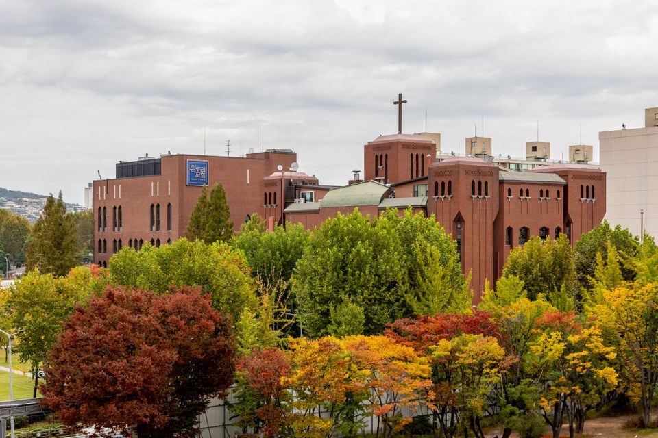 Seoul Providence School and Onnuri Church buildings in Seoul surrounded by autumn trees, showcasing its red-brick architecture and large rooftop cross
